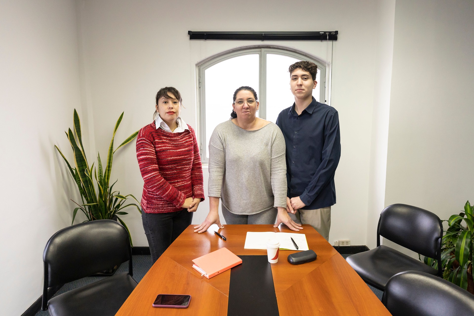 Grupo de empleados de pie al final de la mesa en la sala de reuniones de la oficina