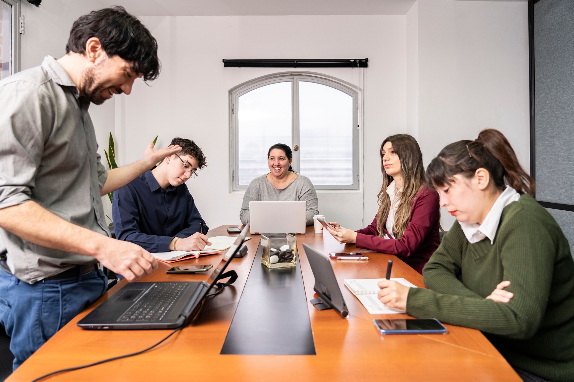 Grupo de empleados sentados alrededor de la mesa de reuniones de la oficina trabajando en sus cuadernos