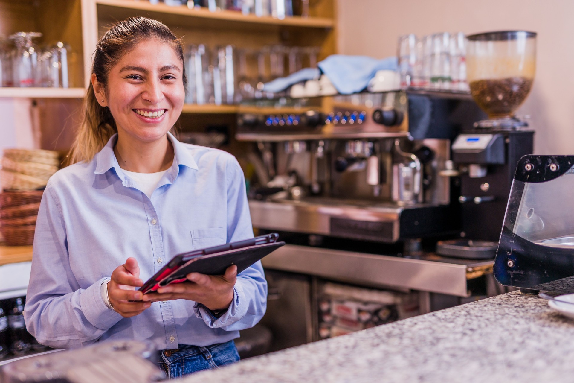 Emprendedor peruano haciendo inventario con pantalla táctil. Joven empresaria latina